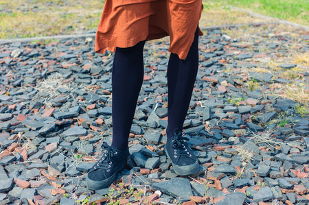The feet and legs of a young woman standing on some gravelの写真素材