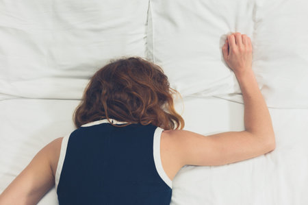 A young woman wearing a dress is passed out on a bed