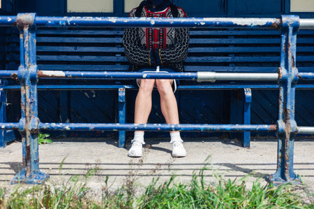 A young woman is sitting at a bus stop on the beach