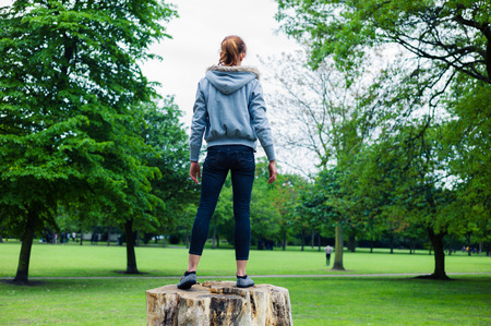 A young woman is standing on a tree trunk in a parkの写真素材