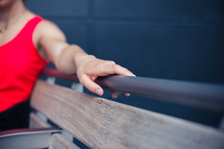 A young woman is resting on a bench outside on a sunny dayの写真素材