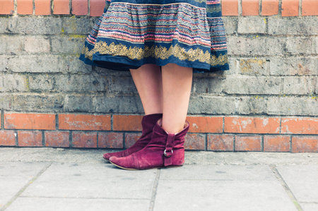 The legs of a young woman wearing a colorful skirt as she is standing in the streetの写真素材