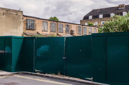 A wooden fence surrounding a building site with old structuresの写真素材
