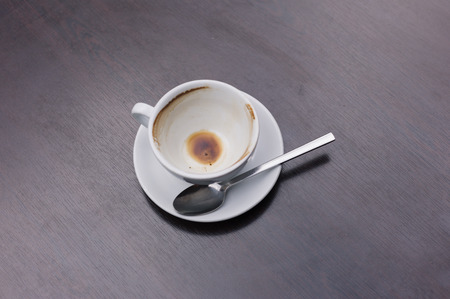 An empty cup of coffee with a spoon on a tableの写真素材