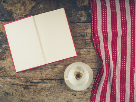 Overhead shot of coffee concept with empty cup, tea towel and an open book with blank pagesの写真素材