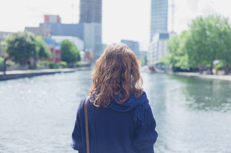 A young woman is standing by a basin in a city