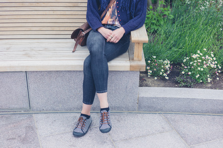 A young woman is relaxing on a bench in the cityの写真素材