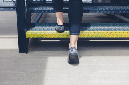 The feet of a young woman as she is walking up some metal stairsの写真素材