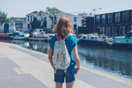 A young woman is standing by a canal in the city on a summer dayの写真素材