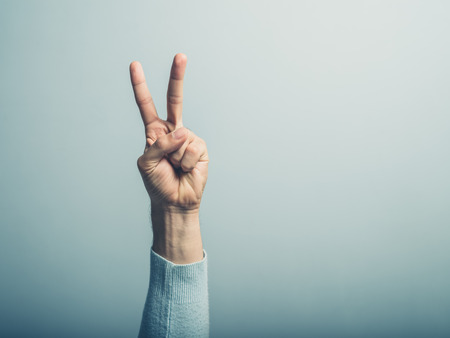 A male hand is displaying the v for victory signの写真素材