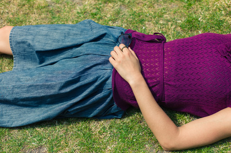 A young woman is lying on the grass in a park and is relaxingの写真素材