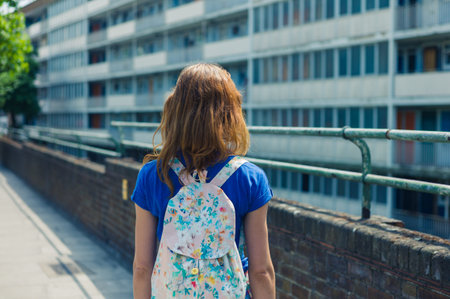 A young woman is looking at an apartment block in the city on a sunny day of summer