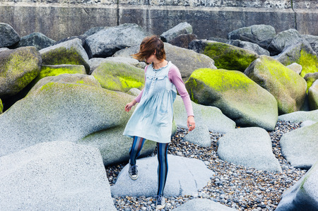 A young woman is walking amongst some vibrant rocks on the coastの写真素材