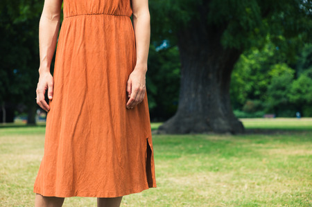 A young woman is standing by a big tree in a parkの写真素材