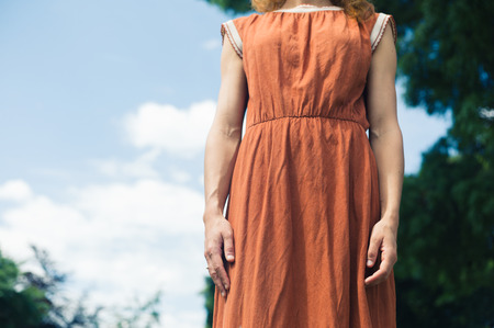 A young woman is standing outside in natureの写真素材
