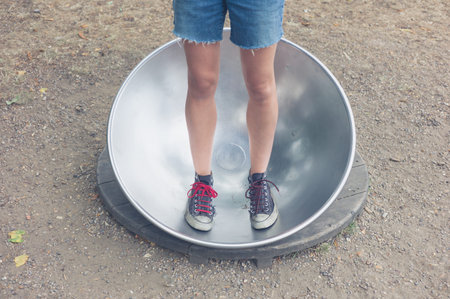 A young woman is standing in a big metal dish outside
