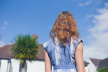 A young woman is standing and relaxing in a residential garden on a sunny summer dayの写真素材