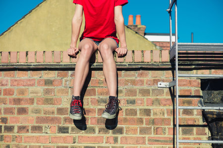 A young woman is sitting and relaxing on a roofの写真素材