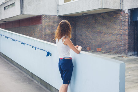 A stylish young woman is standing in the yard of a housing estate