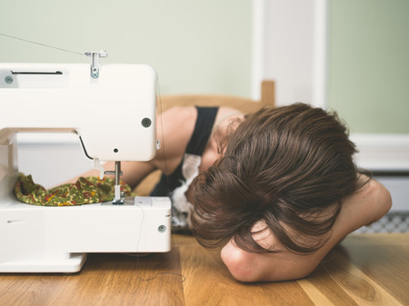A young woman is asleep by her sewing machineの写真素材