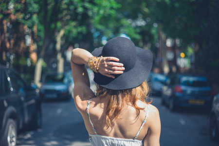 A young woman wearing a hat is walking in the streetの写真素材