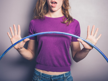 A happy young woman is holding a hula hoopの写真素材
