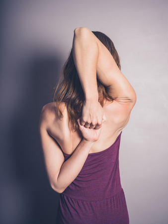 A young woman is stretching her arms behind her back in a yoga poseの写真素材