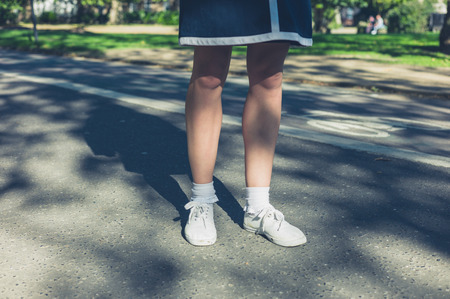 The legs of a young woman standing on a path in a parkの写真素材