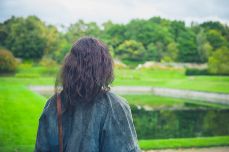 A young woman is exploring a formal garden with a small pond