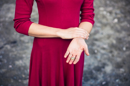 A young woman is standing on the beach and is holding a shell she foundの写真素材