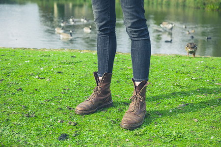 The legs of a young person standing by a pond with birdsの写真素材