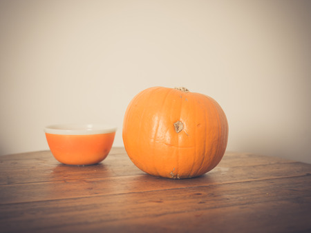 A pumpkin and a bowl on a tableの写真素材