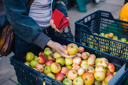 A young woman is selecting and buying an apple at the marketの写真素材