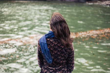 A young woman is sitting by the sea in autumnの写真素材