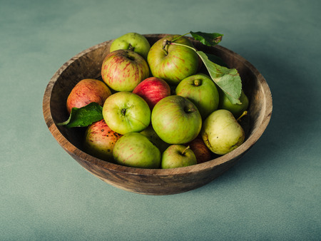 A bowl of freshly picked green apples on a green tableの写真素材