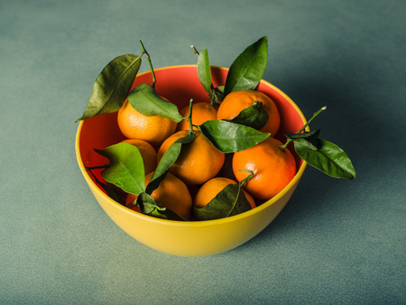 A small bowl of fresh oranges on a green tableの写真素材