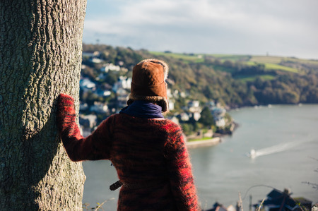 A young woman is hiking on a hill above a small town by the seaの写真素材