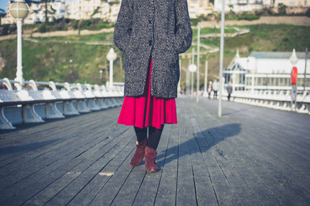 A young woman is walking on the pier in autumn or winter