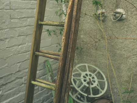 An old wooden ladder outside against a wallの写真素材