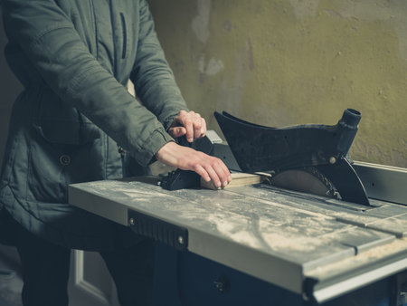 A young person is operating a tablesaw in a hallway