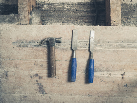 A hammer and two chisels on a wooden floorの写真素材