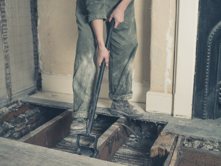 A young woman wearing a boiler suit is taken up the floor boards in a Victorian houseの写真素材