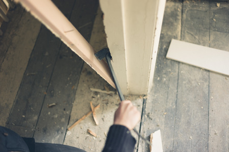 Close up on a worker's hand breaking a door frame with a crowbarの写真素材