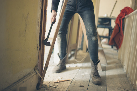 A worker is breaking down a door frame with a crowbarの写真素材