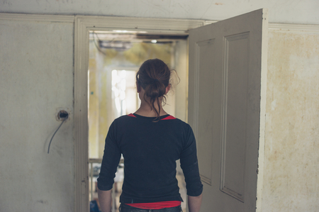 A young woman is standing by a door frame in a house that is being renovatedの写真素材