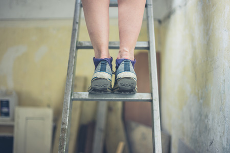 The legs of a young woman standing on a ladder to the loftの写真素材