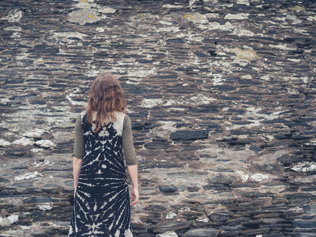 A young woman is standing by a rubble wallの写真素材