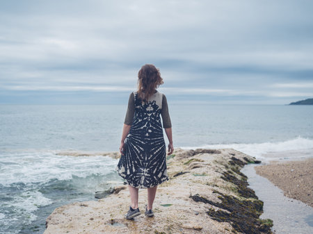 A young woman is standing by the seaの写真素材
