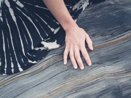 The hand of a young woman is touching a beautioful rock surfaceの写真素材