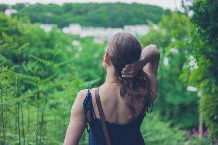 Young woman standing in nature with her hand grabbing her hairの写真素材